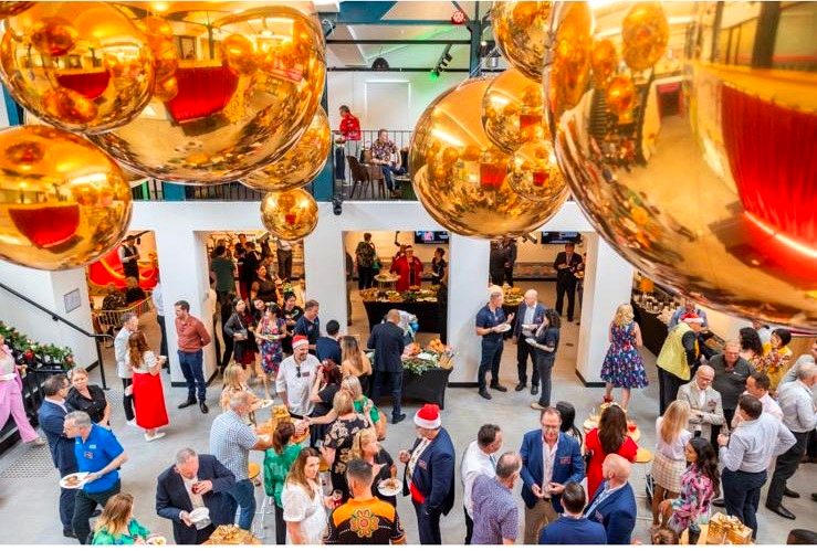 Guests enjoying a corporate Christmas party under a gold bauble installation